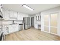 Beautiful white kitchen with stainless steel appliances, granite countertops, and wood grain tile flooring at 402 Summit Ridge Ter, Lawrenceville, GA 30046