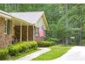 Classic brick home detail featuring an American flag, rocking chairs, and manicured landscaping at 544 W Macedonia Church Rd, Oxford, GA 30054