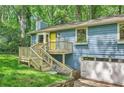 Blue home featuring a wooden porch and a convenient garage, nestled in a serene, wooded setting at 2336 Vistamont Dr, Decatur, GA 30033