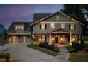 Charming two-story home with manicured landscaping, exterior lighting, and three car garage at dusk at 525 E Main St, Buford, GA 30518