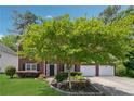 Beautiful brick home featuring a mature tree in the front yard, and a two-car garage at 6034 Farmwood Se Way, Mableton, GA 30126