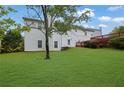Spacious backyard with a large green lawn, mature tree, and a red wooden deck at 6031 Hitt Lake Ct, Stone Mountain, GA 30087