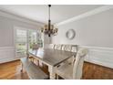 Bright dining room featuring a wooden table, upholstered chairs, and a stylish chandelier fixture at 10000 Groomsbridge Rd, Johns Creek, GA 30022