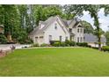 Beautiful home with a large, green front lawn and attached two-car garage in a wooded setting at 10000 Groomsbridge Rd, Johns Creek, GA 30022