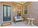 Inviting front porch with brick detail, a bench, table, and decorative accents at 120 Laurel Rdg, Canton, GA 30114