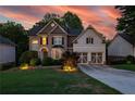 Elegant two-story home featuring a brick facade, a well-kept lawn, and a two-car garage at sunset at 6217 Millstone Trl, Douglasville, GA 30135