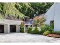 Exterior view of the home featuring a three-car garage, white brick, and mature landscaping at 1 Habersham Nw Way, Atlanta, GA 30305