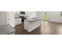 Modern kitchen with a central island, stainless steel appliances, and stylish wood flooring at 25 Amberjack Trl, Covington, GA 30016