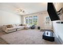 Bright and airy living room with a cozy sectional sofa, large windows, and a ceiling fan for comfortable living at 741 Jackson Ct, Social Circle, GA 30025