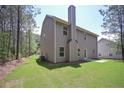 Well-maintained backyard with a view of the home's exterior, featuring a chimney and lush green space surrounded by trees at 48 Beaver Pt, Villa Rica, GA 30180