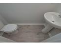 Well-lit half bathroom featuring modern fixtures, including a pedestal sink and toilet at 48 Beaver Pt, Villa Rica, GA 30180