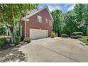 A well-maintained two-car garage with a large driveway and basketball hoop, nestled in a lush, wooded landscape at 6009 Castleton Mnr, Cumming, GA 30041