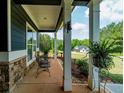 Spacious front porch with seating, stone pillars, and a view of the manicured front yard and surrounding landscape at 1056 Riverstone Dr, Social Circle, GA 30025