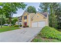 The lovely yellow two-story home features a spacious driveway and an attached two-car garage at 7113 Ambercrest Ct, Austell, GA 30168