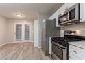 An airy kitchen showcasing stainless steel appliances, light gray flooring, and access to the backyard patio at 7113 Ambercrest Ct, Austell, GA 30168