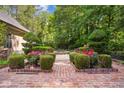 Beautiful backyard featuring lush landscaping, manicured bushes, brick pathways, and vibrant pink roses at 973 Peachtree Battle Ave, Atlanta, GA 30327