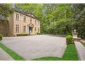 A large brick driveway leads to an elegant stone home surrounded by lush greenery and manicured hedges at 973 Peachtree Battle Ave, Atlanta, GA 30327