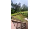 A view from the wooden deck stairs with lush green lawn surrounded by mature trees in the backyard at 585 Station View Run, Lawrenceville, GA 30043