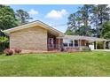 Single story home with stone details, a red door, brick, and well maintained lawn, with a carport at 2315 Tuxedo Se Dr, Marietta, GA 30067