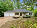 Inviting home featuring a two-car garage, neutral siding, black shutters, and a landscaped garden at 6026 Woodcreek Dr, Woodstock, GA 30188