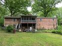 Back exterior of brick home with large backyard, screened porch and cluttered patio at 1481 Pine St, Stone Mountain, GA 30087