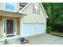 Inviting front entrance features a two-car garage, beautiful landscaping, and a decorative front door at 237 River Pass Ct, Dacula, GA 30019