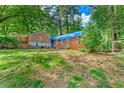 Exterior shot of a brick home with blue tarp, showing its setting on a spacious lot with lush trees at 2180 Rexford Dr, Decatur, GA 30034