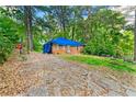View of a red brick home with tarp, amidst the trees, showcasing potential project and backyard at 2180 Rexford Dr, Decatur, GA 30034