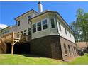 Rear view of a house featuring a wooden deck overlooking a spacious backyard with a brick facade at 3730 Reserve Overlook (Lot 8) Way, Cumming, GA 30041
