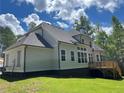 Rear view of a house featuring a dark roof, siding, and a wooden deck overlooking a spacious backyard at 3730 Reserve Overlook (Lot 8) Way, Cumming, GA 30041