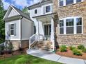 Charming home featuring a stone facade and welcoming front entrance with stylish door and well-manicured landscaping at 3730 Reserve Overlook (Lot 8) Way, Cumming, GA 30041