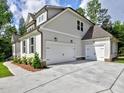View of the three car garage with white doors, a concrete driveway, and partial side view of the home at 3730 Reserve Overlook (Lot 8) Way, Cumming, GA 30041