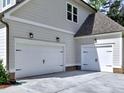 Two car garage with white doors and black hardware with exterior lights and gray siding at 3730 Reserve Overlook (Lot 8) Way, Cumming, GA 30041