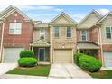 Inviting two-story brick townhome features a one-car garage, lush landscaping, and a welcoming front entrance at 1622 Honeysuckle Path, Conyers, GA 30012