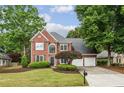 Charming brick home with a manicured lawn, mature trees, a two-car garage, and beautiful curb appeal at 321 Woodbrook Crst, Canton, GA 30114