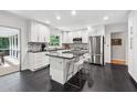 Modern kitchen featuring white cabinetry, stainless steel appliances, an island with bar seating, and black tile floors at 500 Read Ln, Atlanta, GA 30328