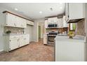 Traditional kitchen with white cabinets, stainless steel appliances, and a tiled backsplash at 588 Benson Hurst Sw Dr, Mableton, GA 30126