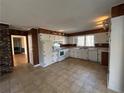 Traditional kitchen featuring wood paneling, white cabinets and appliances, and tile flooring at 1053 Allgood Rd, Stone Mountain, GA 30083