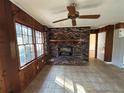 Cozy living room featuring a brick fireplace, ceiling fan, and large windows at 1053 Allgood Rd, Stone Mountain, GA 30083
