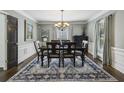 Elegant dining room with wainscoting, dark wood flooring, and a stylish chandelier at 3715 Borning Ct, Johns Creek, GA 30022