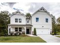 Stunning two-story white farmhouse exterior with a covered porch and a two car garage at 129 Henley St, Canton, GA 30114