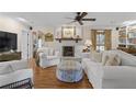 Cozy living room with wood floors, white furniture, fireplace, ceiling fan, and built-in shelves at 11190 Hembree Springs Dr, Roswell, GA 30076