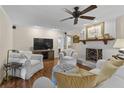 Inviting living room featuring a fireplace, tv, ceiling fan, and comfortable white seating at 11190 Hembree Springs Dr, Roswell, GA 30076
