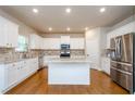 Bright kitchen with white cabinetry, stainless steel appliances, a center island, and hardwood floors at 3405 Linstead Ct, Loganville, GA 30052
