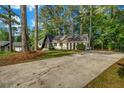 Striking A-frame home featuring a long driveway, mature trees, and lush green lawn at 4274 Smithsonia Ct, Tucker, GA 30084