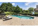 Sparkling in-ground pool with waterfall feature, surrounded by brick patio and mature landscaping at 4830 Westgate Dr, Cumming, GA 30040