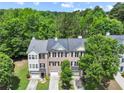 A view of the townhome showing the garage doors and well-manicured lawn with mature trees in the background at 2138 Mill Garden Run, Buford, GA 30519