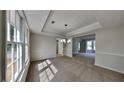 Bright dining room features large windows, neutral walls, plush carpet, and decorative tray ceiling at 4954 Penscot Way, Stone Mountain, GA 30088