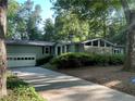 View of the home's exterior with an attached garage and a long driveway, surrounded by mature trees at 1260 Willeo Creek Dr, Roswell, GA 30075