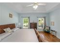 Serene main bedroom with light blue walls, tray ceiling, hardwood floors, and two windows with views of the yard at 1605 Little Lisa Ln, Snellville, GA 30078